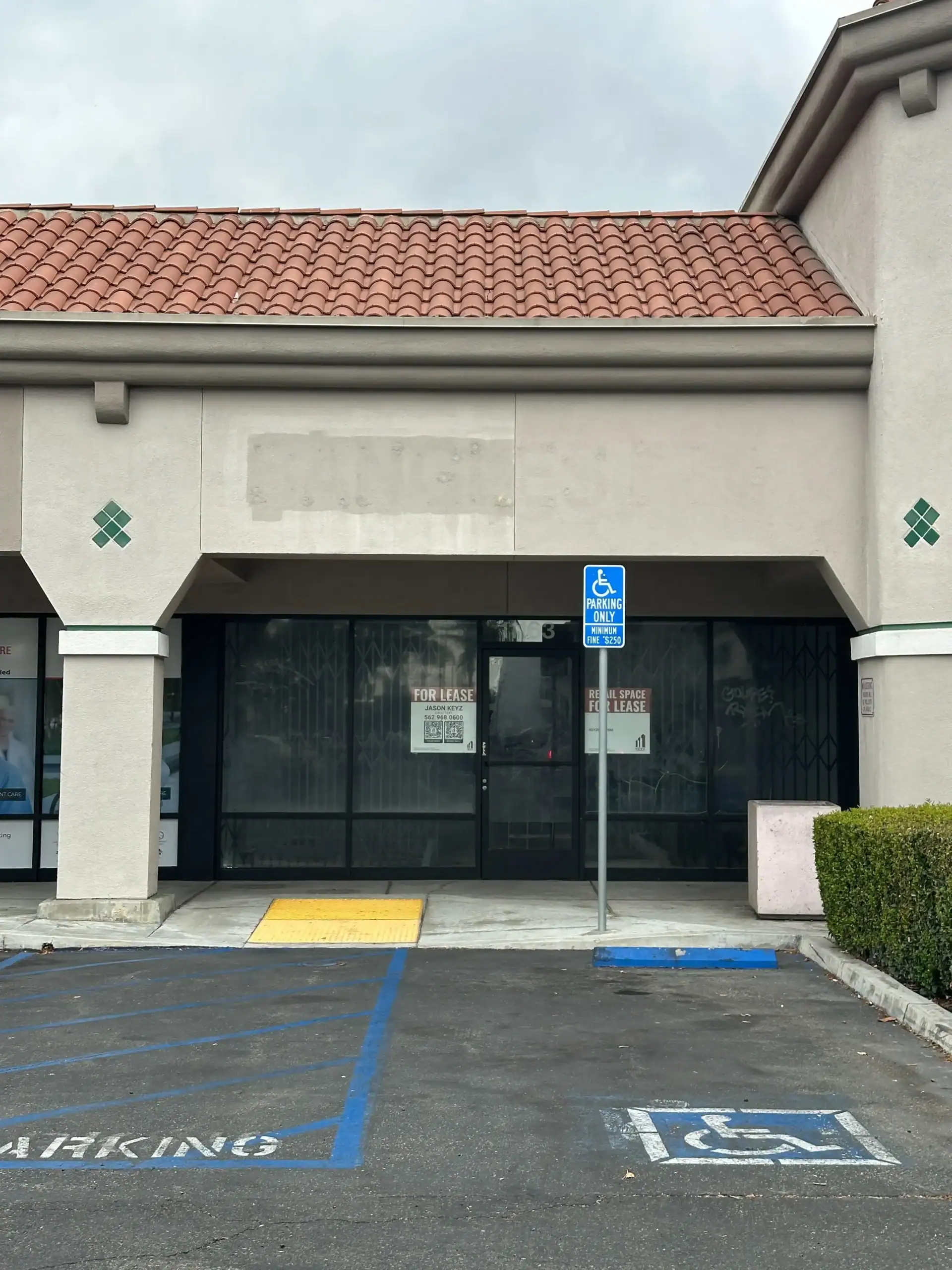 Retail space available for lease at Santa Fe Springs Marketplace, featuring a prominent "FOR LEASE" sign, accessible entrance, and surrounding parking area.