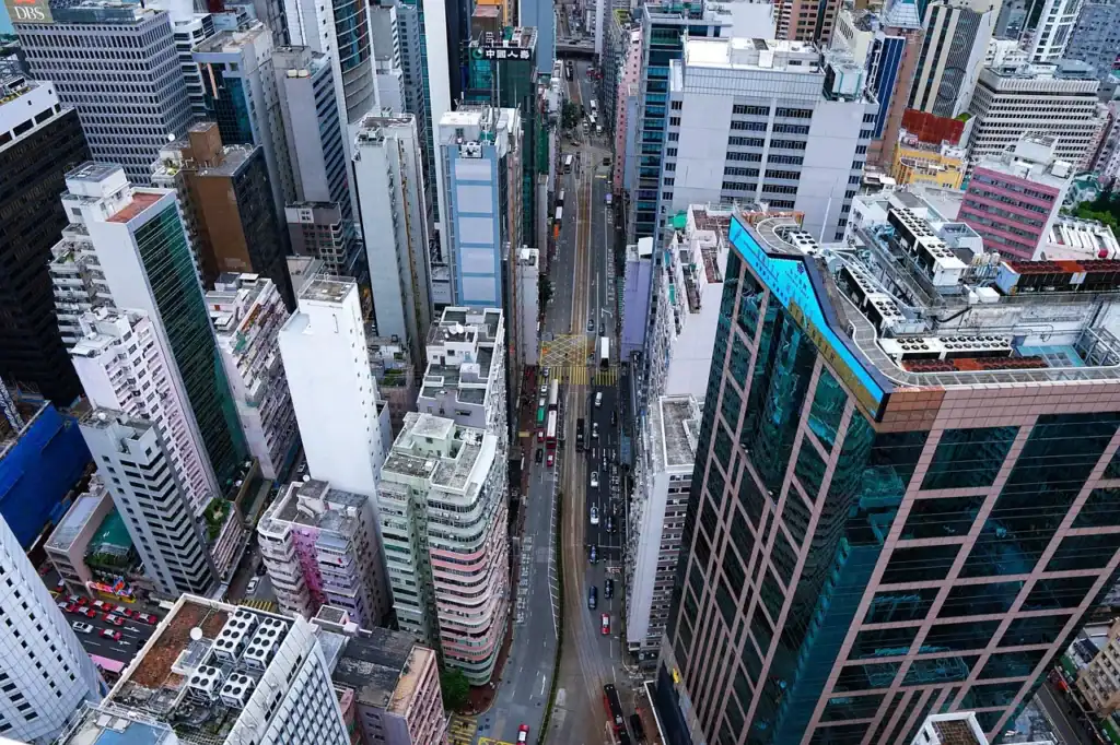 Aerial view of a busy city center with tall skyscrapers, glass office towers, and narrow streets filled with traffic in a modern urban business district.