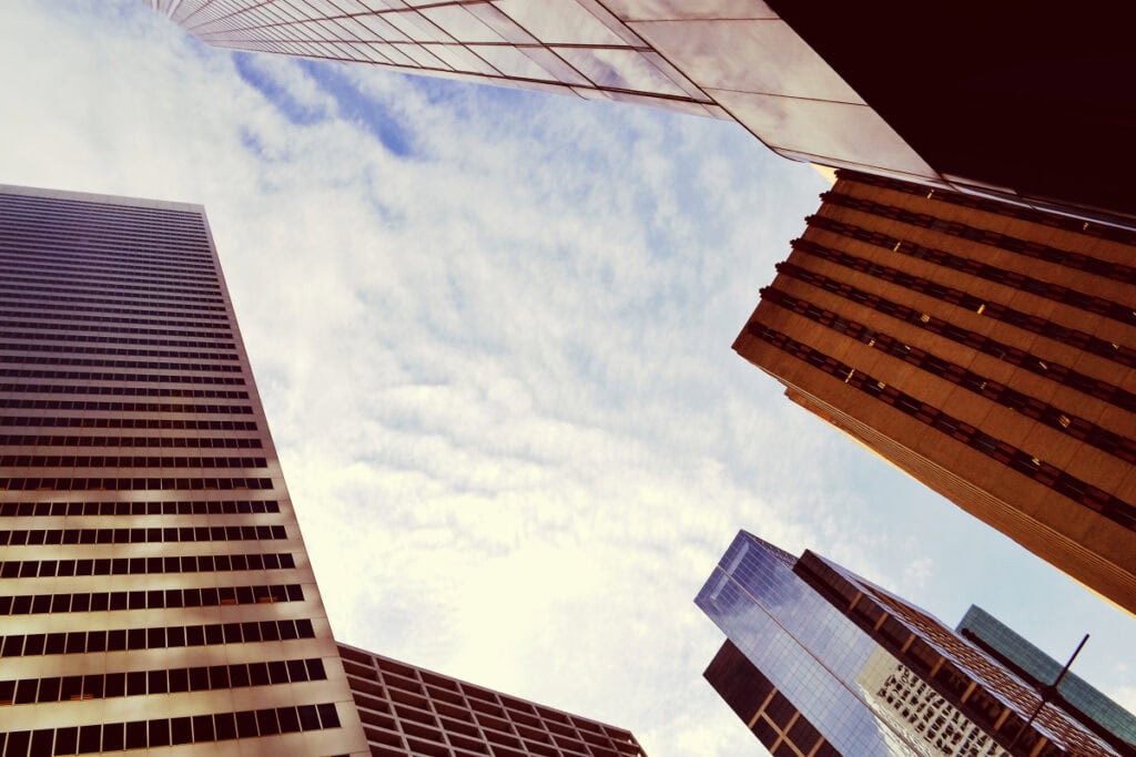 Upward view of tall Commercial buildings in a city skyline representing market growth and urban economic trends.