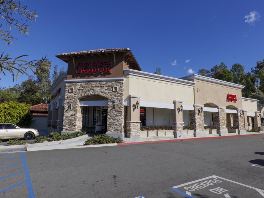 Los Alisos Village neighborhood retail center on Los Alisos Blvd in Mission Viejo, California, with storefronts, stone-clad columns and parking directly in front of the units