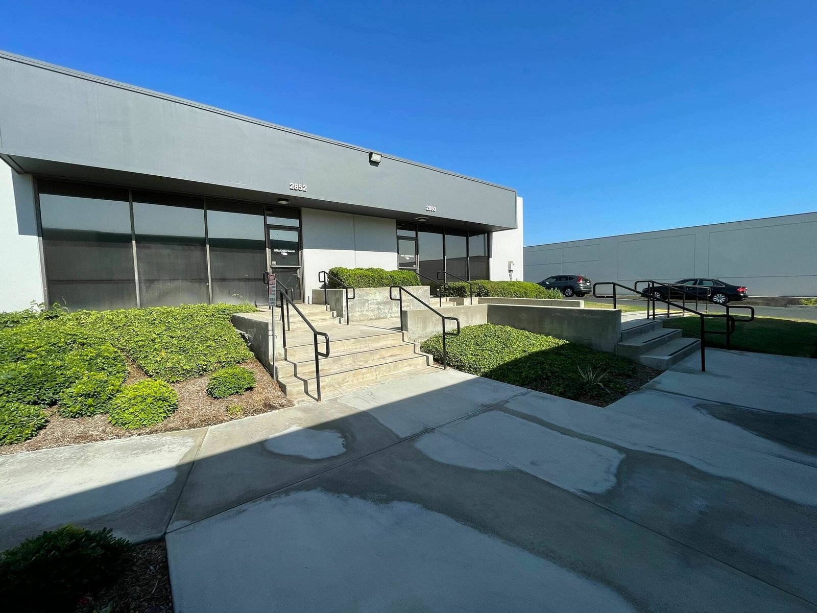 Suite entrances at Southern Steel Brea Center in Brea, California, with glass storefronts, a landscaped walkway and stepped access to two ground-floor units