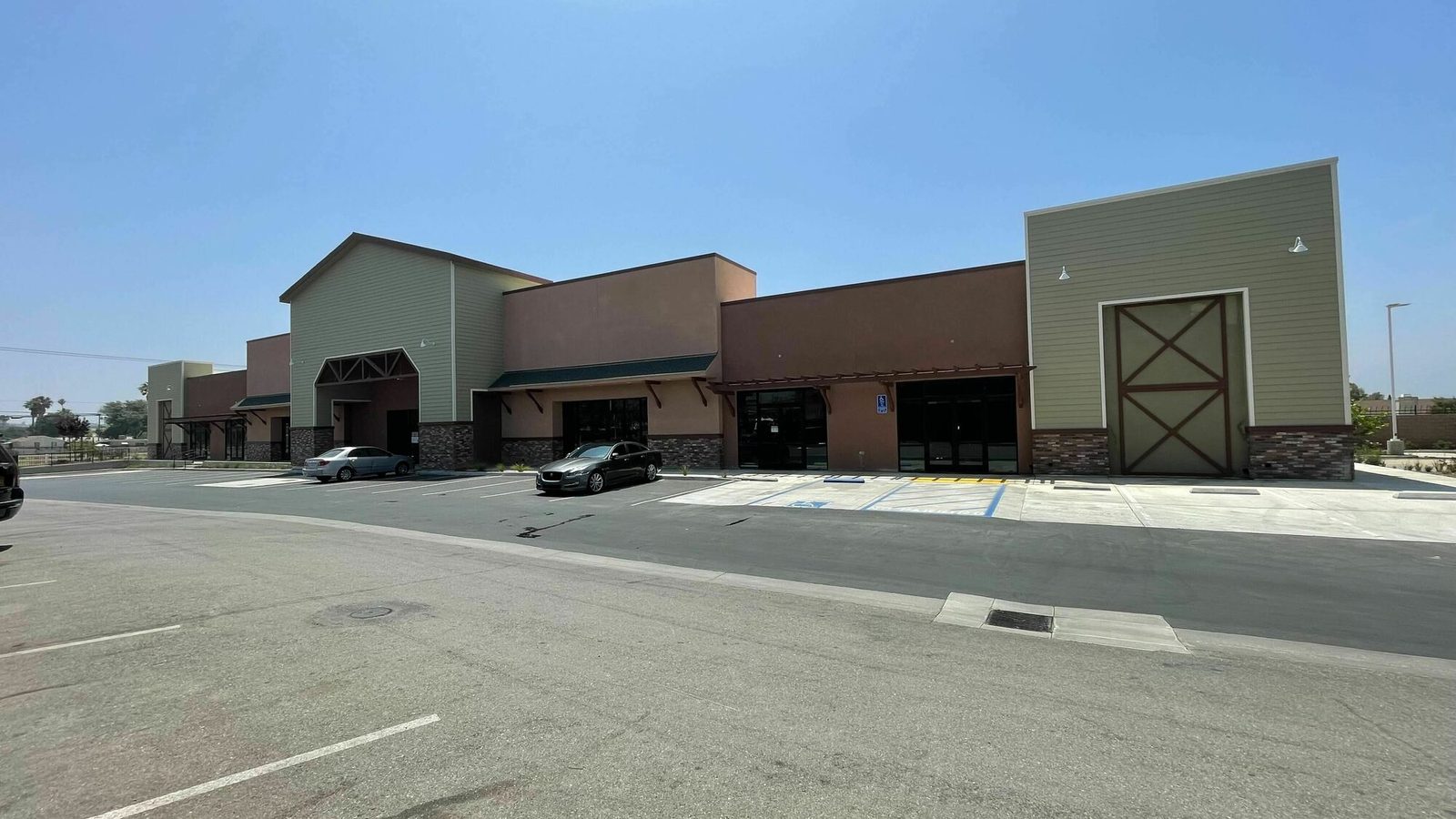Valley Square, 8254 Mission Blvd, Jurupa Valley - olive green and brown retail buildings with a stone base, a barn-door detail and surface parking